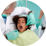 young girl with yellow apron receiving dental treatment