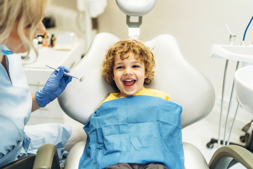 happy little boy sitting in dentist chair