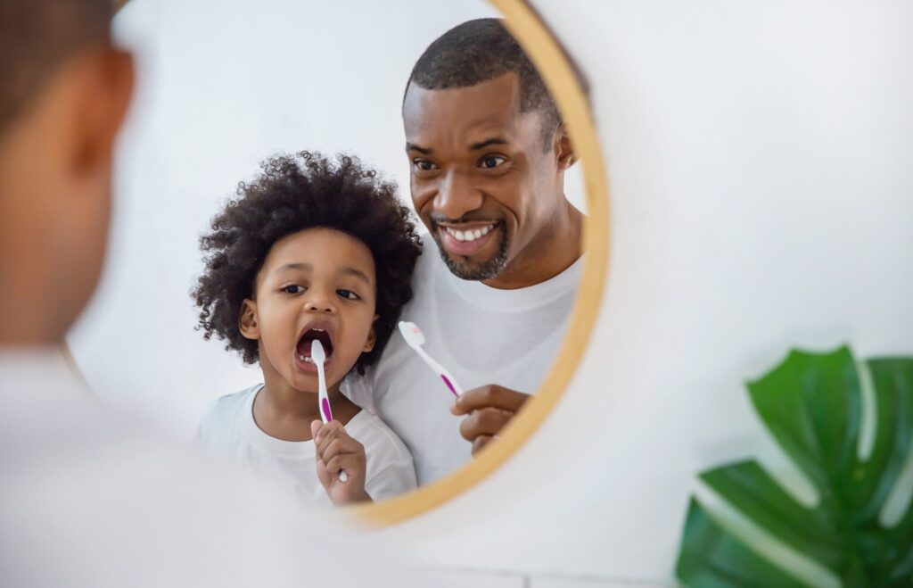 man brushing teeth with young boy