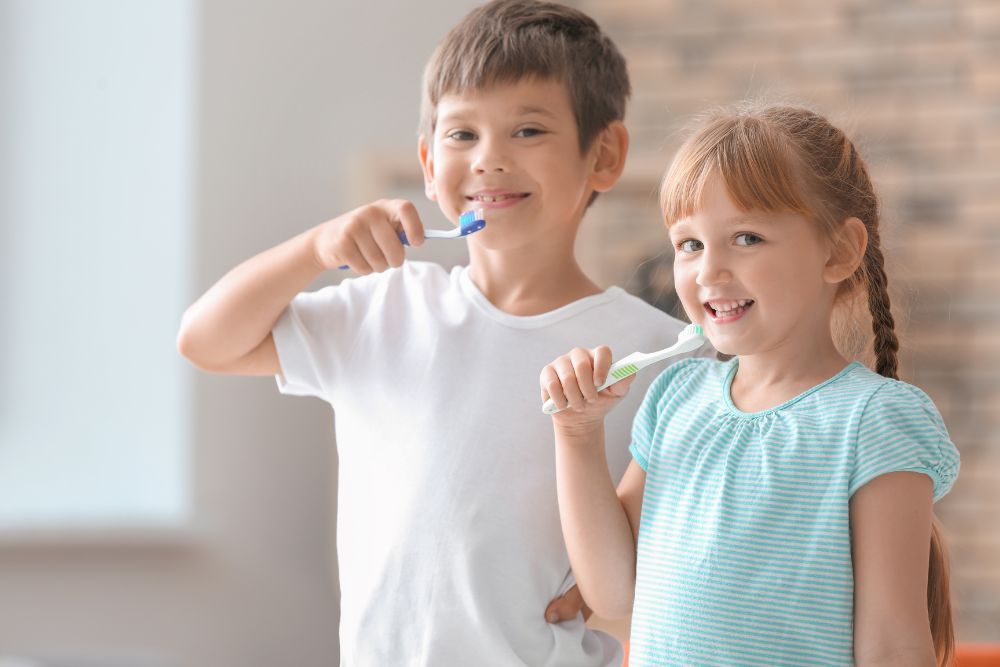 two young child brush their teeth and smile