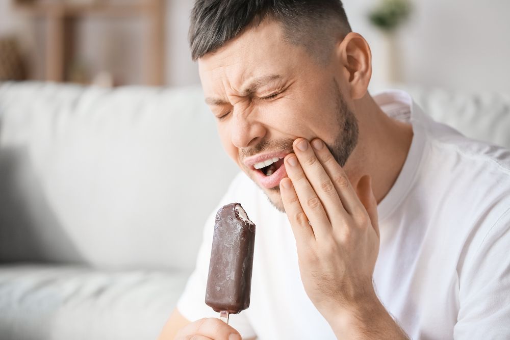 man experiences tooth pain while eating ice cream