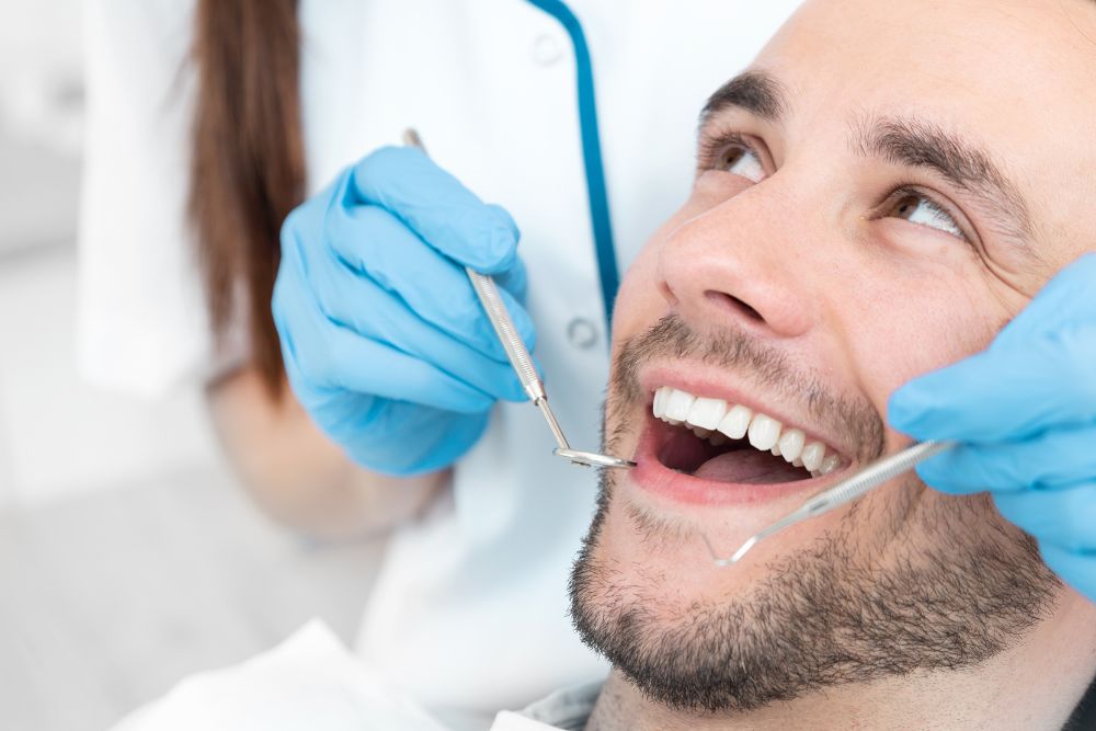 man smiles as dentist cleans teeth