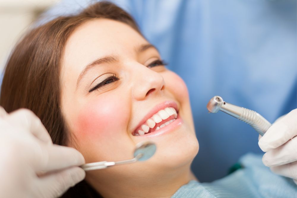 woman smiles as dentist cleans teeth