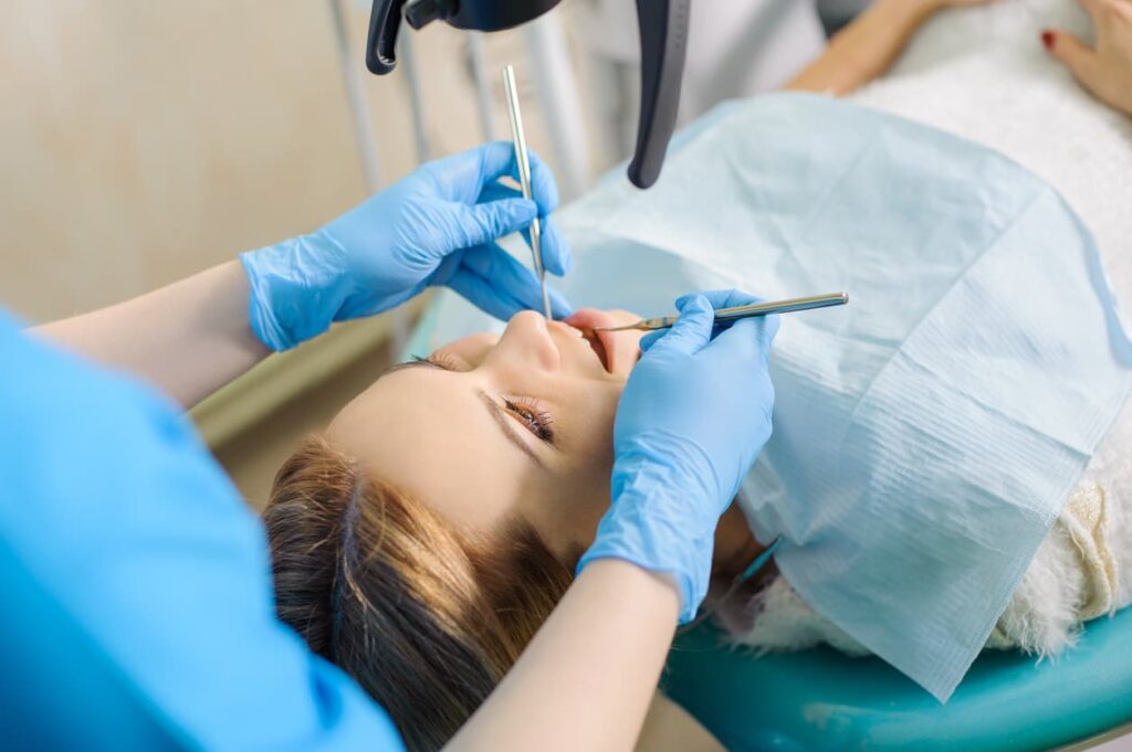 Dentist using tools to examine a patient’s teeth during a procedure