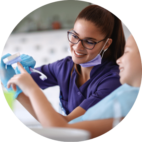 Dental hygienist showing a child how to brush teeth during a visit
