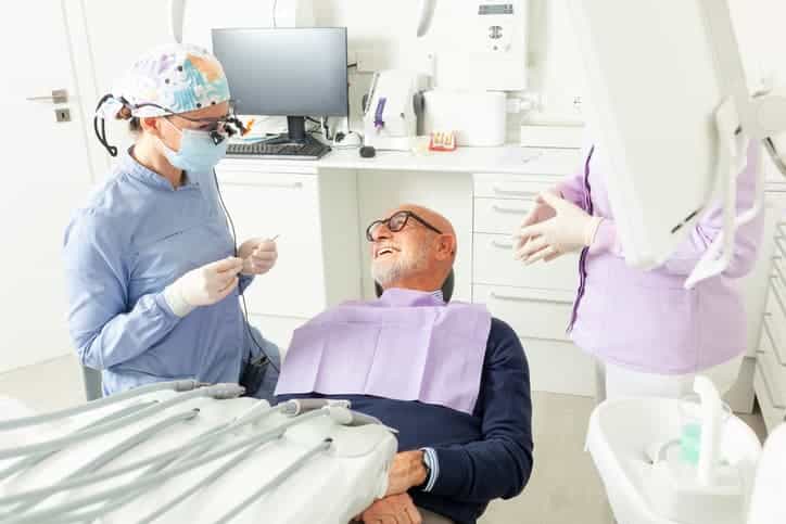 Dentist speaking with a patient in a dental chair before treatment