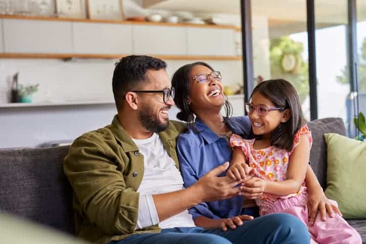 Family laughing together while sitting on a couch at home