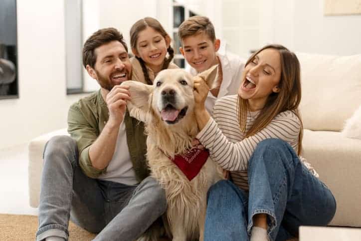 Family playing with their dog while sitting together on the floor at home