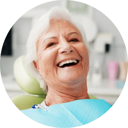 Senior woman smiling in a dental chair after a checkup wearing a dental bib