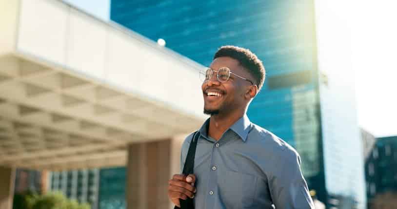 Man smiling while walking outdoors with office buildings in the background
