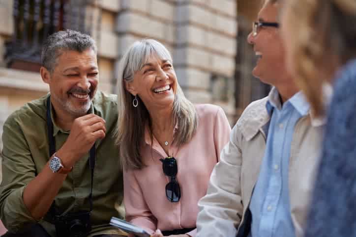 Group of older adults laughing together while sitting outdoors