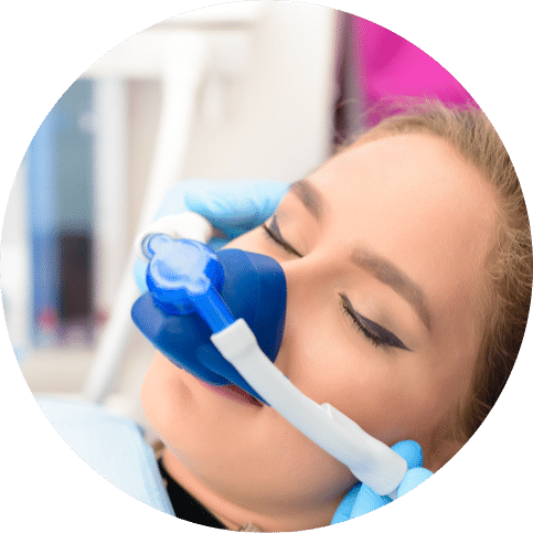 Patient wearing nitrous oxide mask receiving sedation during dental procedure in clinic