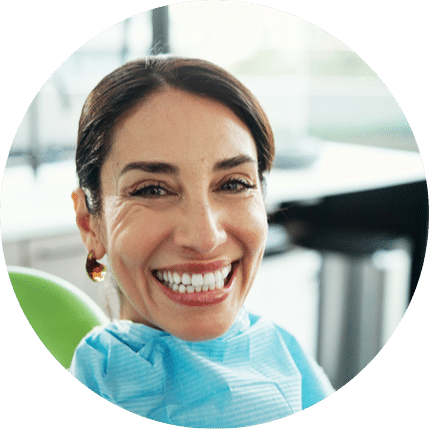 Smiling woman sitting in dental chair after checkup wearing a dental bib