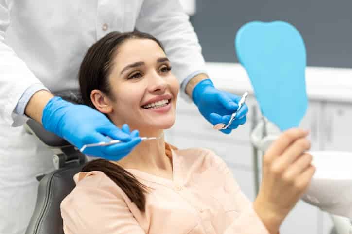 Woman smiling and looking in a mirror during a dental exam
