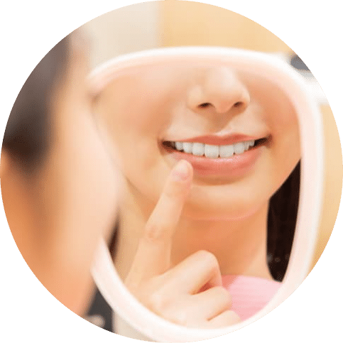 Woman pointing at her teeth while looking in a mirror