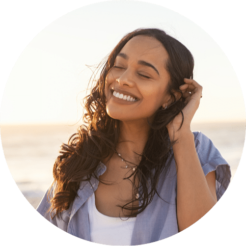 Woman smiling with eyes closed while standing on a beach