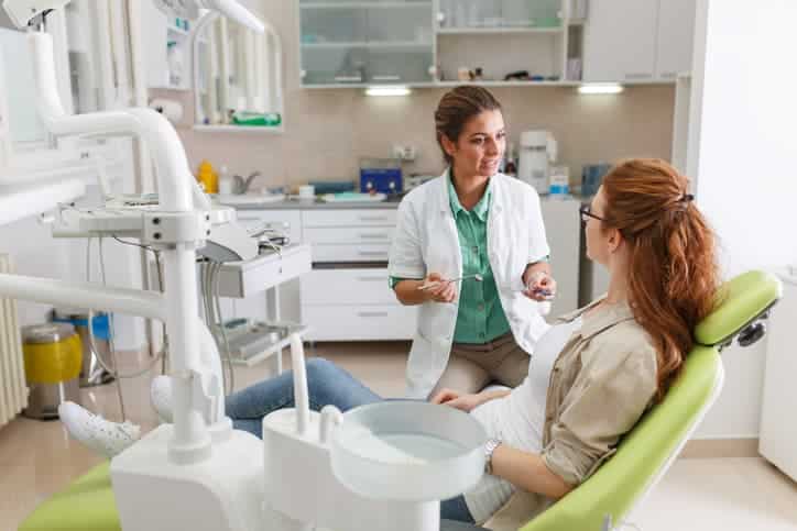 A dentist speaks with a patient seated in a dental chair before treatment. The image highlights patient education, treatment planning, open communication, and a comfortable, welcoming dental care experience.