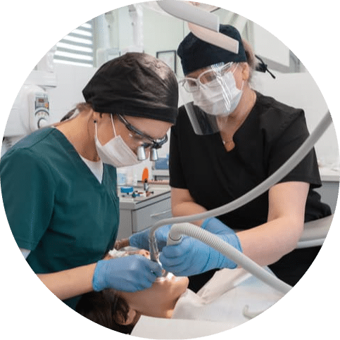 Dentist and dental assistant working together to provide treatment for a patient, demonstrating teamwork, precision, and comprehensive care in a modern dental clinic.