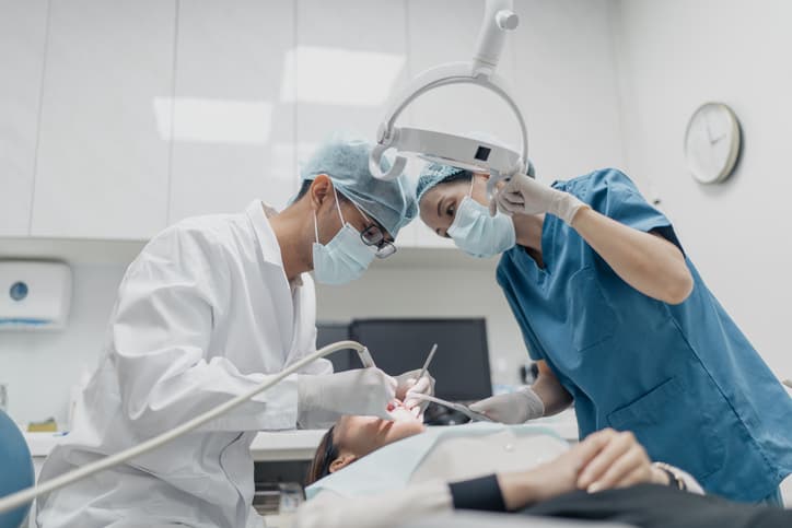 Dentist and dental assistant working together to treat a patient in a modern dental clinic, demonstrating coordinated care, precision, and professional dental treatment.