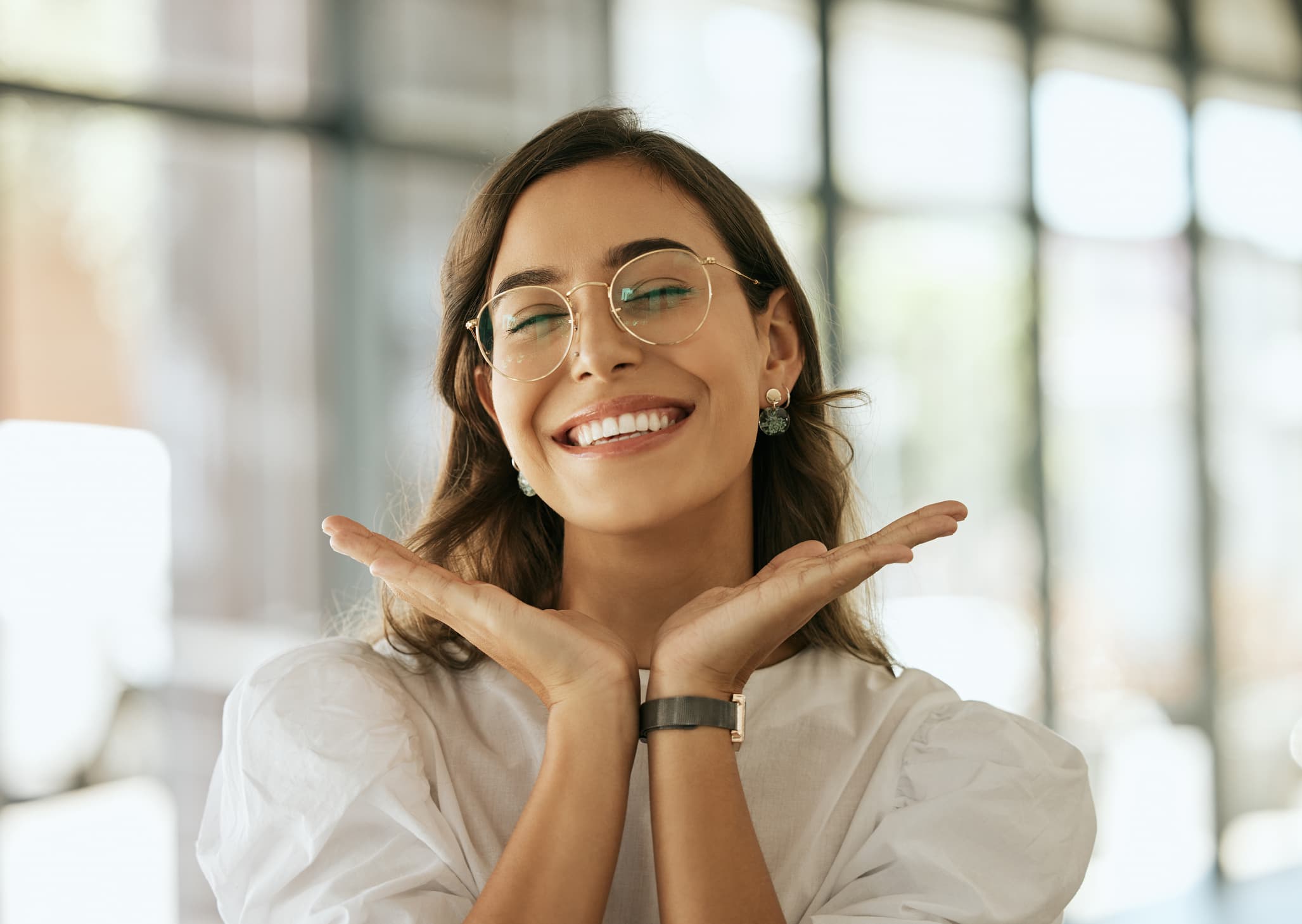 Smiling woman with bright, healthy teeth posing confidently with her hands under her face, representing the confidence and improved oral health that come with quality dental care.