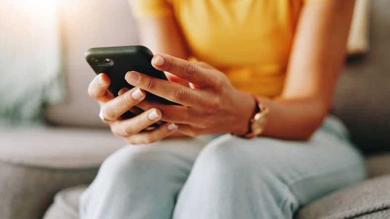 Person using a smartphone at home, representing convenient online dental appointment booking and easy access to dental care.