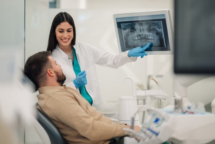 Dentist reviewing a patient's digital dental X-ray during a consultation, explaining findings and discussing personalized treatment options in a modern dental clinic.