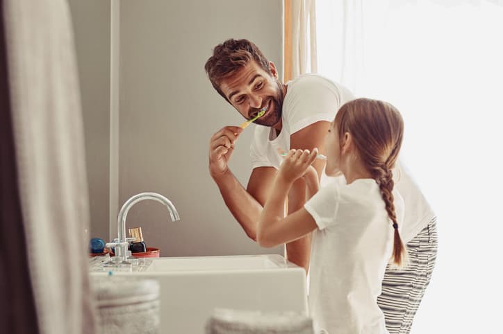 Parent and child brushing their teeth together at home, promoting healthy oral hygiene habits, preventive dental care, and lifelong family dental wellness.
