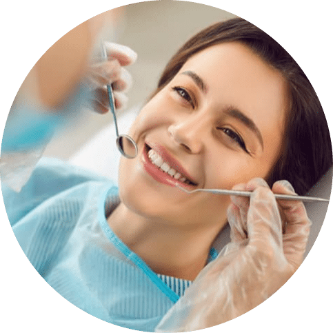 Dental professional examining a smiling patient’s teeth with a mirror and dental instrument during a routine oral health checkup.