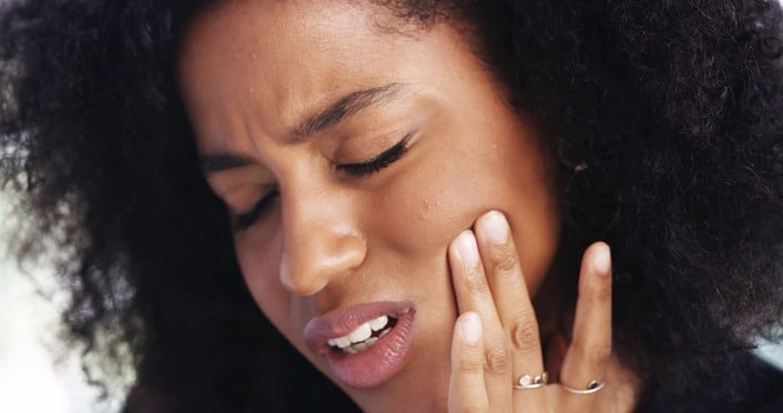 Woman holding her cheek in pain from a dental emergency