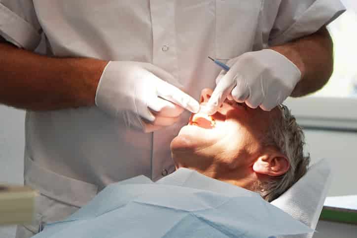Dentist examining and treating an older patient’s tooth, representing professional dental crown preparation and restorative dental care