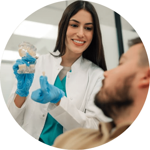 Dentist showing a patient a dental model and explaining how a dental crown can restore a damaged or weakened tooth