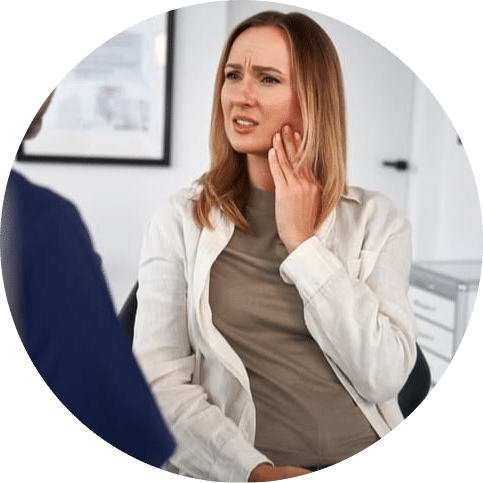 Woman experiencing tooth or jaw pain while discussing her symptoms with a dental professional during an appointment