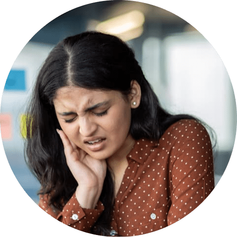 Woman holding her cheek in discomfort while experiencing tooth or jaw pain that may require dental care